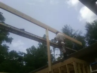 Carpenter setting a ridge beam over a new addition frame — Ice Dam Removal by Roofing Brothers in Lynd