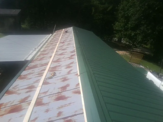 Old rusted panels beside newly installed green metal roofing — Wind Damage Roof Repair by Roofing Brothers in Lynd