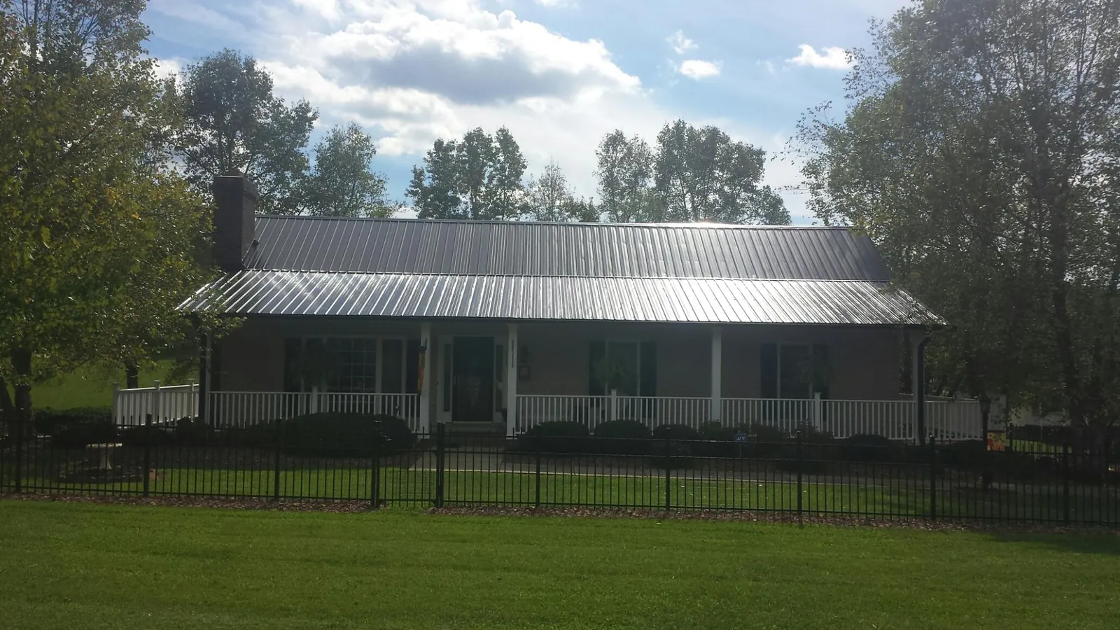 Gray metal roof on a brick ranch with a full width front porch — Gutter Guard Installation work by our crew in Lynd