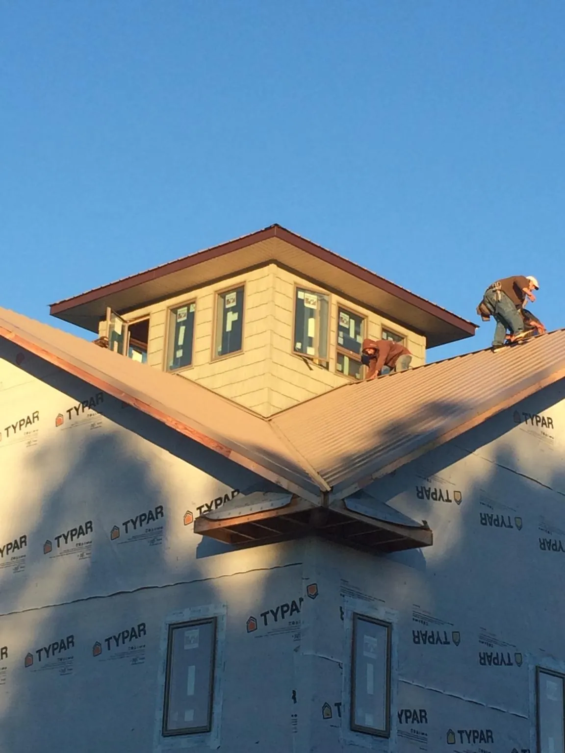 Roofers working around a rooftop cupola on a new metal roof at sunset — Roof Waterproofing in Lynd by Roofing Brothers